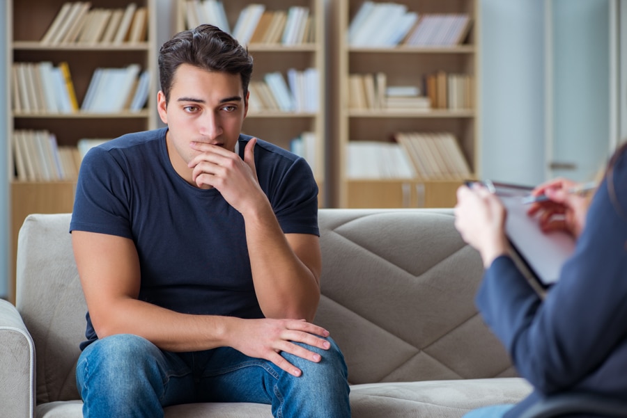 Young man sitting on a couch while receiving cognitive behavioral therapy